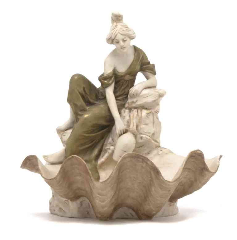 A Royal Dux Porcelain Figural Group, Height 10 in: A Royal Dux Porcelain Figural Group, having a robed maiden filling a ewer at a spring outlet above the shell form bowl. Height 10 inches.