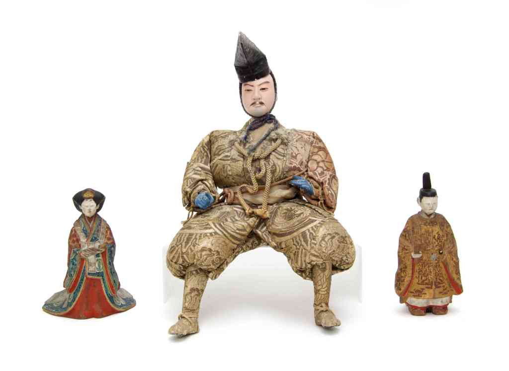 A Japanese Silk and Papier Mache Figure, Height o: A Japanese Silk and Papier Mache Figure, depiciting a warrior in embroidered clothing holding a sword in one hand, together with two polychrome decorated carved wood figures. Height of tallest 14 1/2 