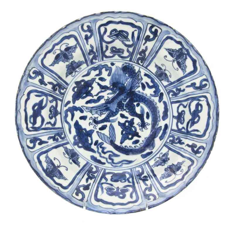 A Chinese Export 'Kraak' Porcelain Charger, Diame: A Chinese Export 'Kraak' Porcelain Charger, having central panel with decoration of a dragon, the border having lotus petal form panels containing various Buddhist emblems and butterflies. Diameter 12