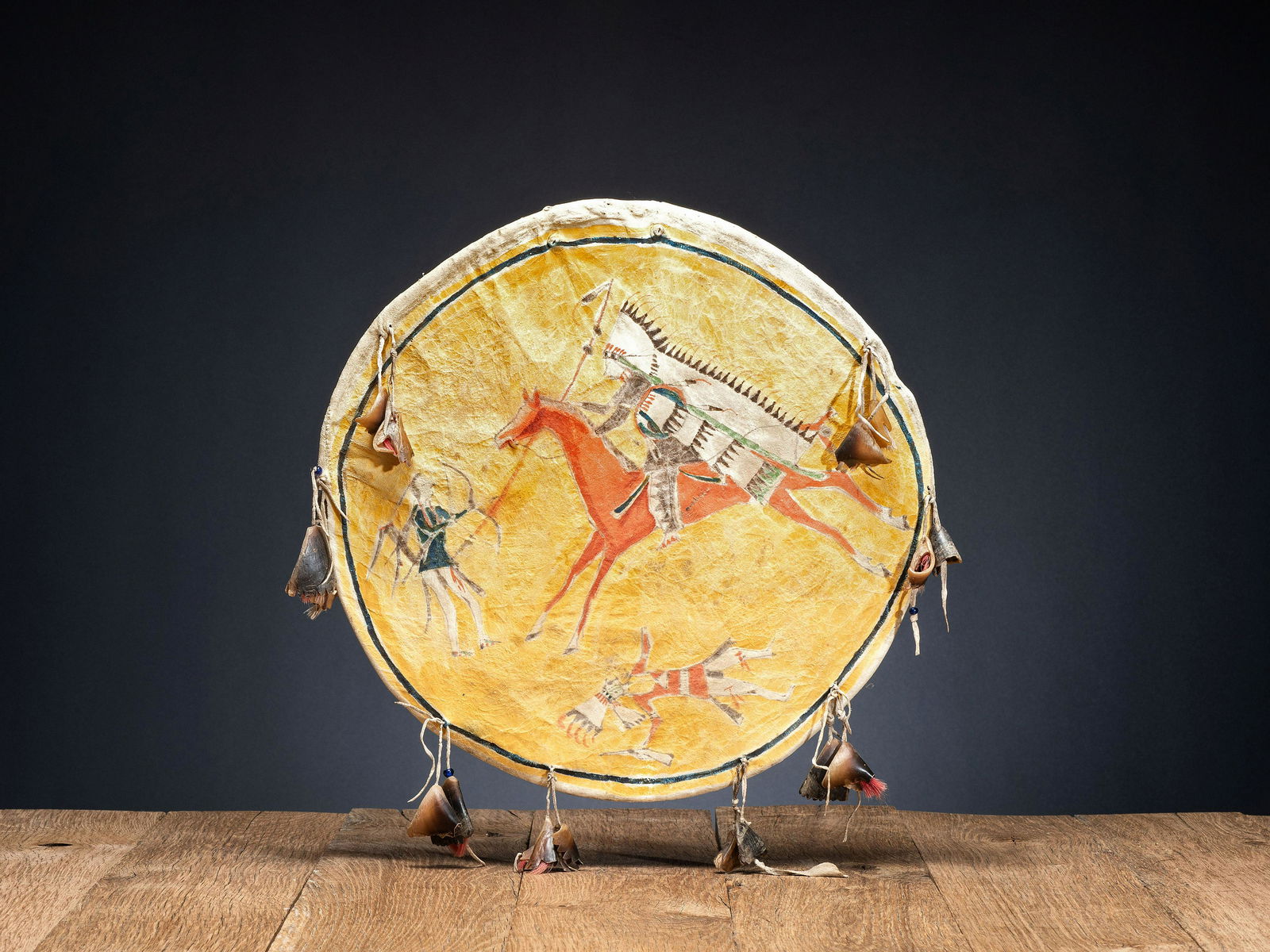 Southern Cheyenne Painted Hide Shield: Southern Cheyenne Painted Hide Shield fourth quarter 19th century cover is made from softly tanned thin hide cover painted in colors of yellow, red, black, and green and depicting a battle scene; pair