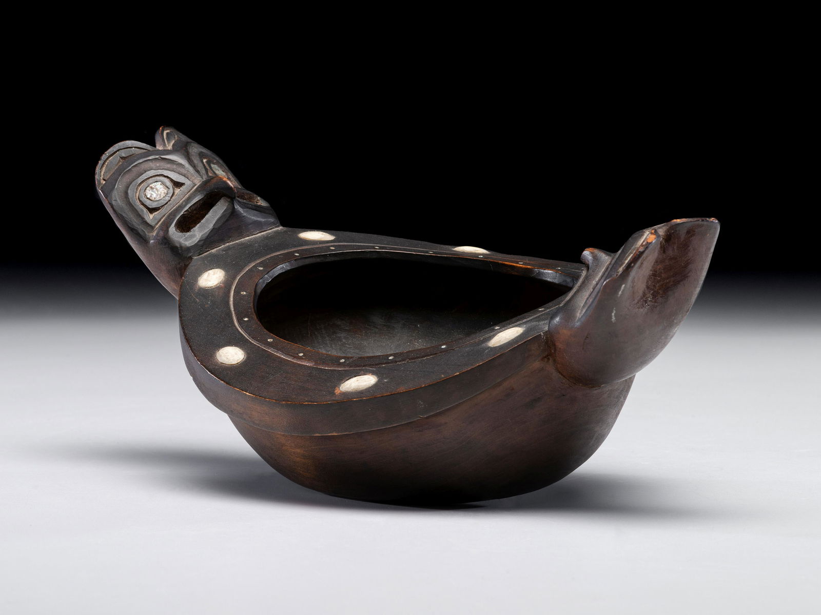 Haida Carved Figural Feast Bowl: Haida Carved Figural Feast Bowl circa 1900 carved with two facing eagle heads having abalone shell eyes; rim of bowl with eight bone insets length 12 inches Property from the Estate of Robert Streett