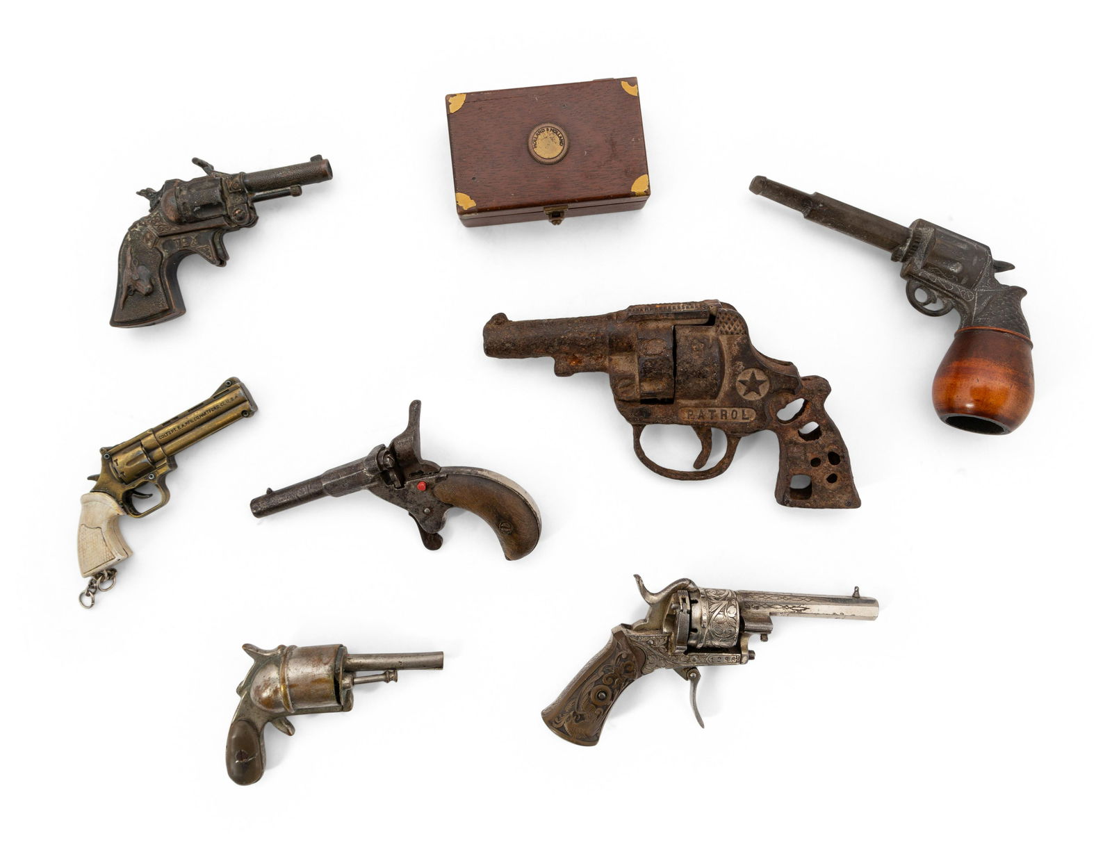 A Group of Eight Miniature Firearms Related Accoutrements: A Group of Eight Miniature Firearms Related Accoutrements 19th/20th Century comprising of a relic patrol cap-gun, two addtional cap guns (one marked Tex), an antique pinfire miniature pistol