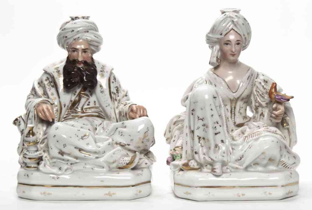 A Pair of Paris Porcelain Figural Candlesticks, Ja: A Pair of Paris Porcelain Figural Candlesticks, Jacob Petit, the seated man with a snake and the seated woman with a bird, each on octagonal pillows, depicted wearing Arab costumes, signed in undergla