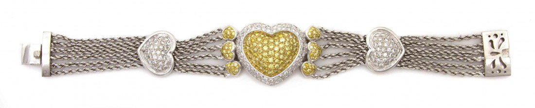 An 18 Karat White Gold, Fancy Color and White Diam: An 18 Karat White Gold, Fancy Color and White Diamond Bracelet, consisting of a central heart shape plaque bordered by six smaller heart shape sections, joined by six rope texture white gold chains bi