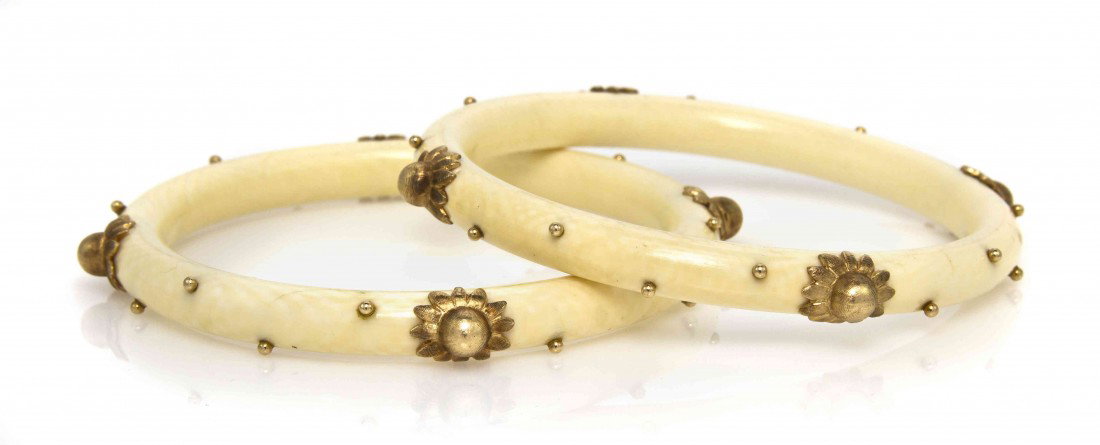 A Pair of 14 Karat Yellow Gold and Ivory Bangle Br: A Pair of 14 Karat Yellow Gold and Ivory Bangle Bracelets, consisting of two ivory bangles accented with flower shaped gold sections and gold beads. 29.95 dwts.