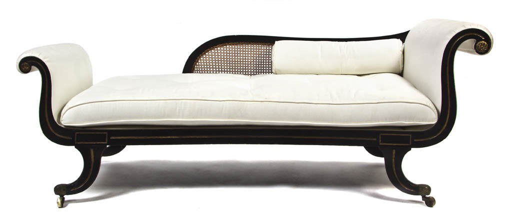 A Regency Ebonized and Parcel Gilt Upholstered Cha: A Regency Ebonized and Parcel Gilt Upholstered Chaise, having a caned back and scrolled ends with carved roundels, raised on downswept legs ending in casters. Width 75 inches.