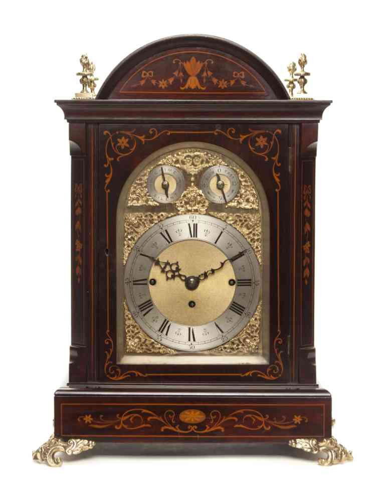 An Edwardian Inlaid Mahogany and Gilt Bronze Mount: An Edwardian Inlaid Mahogany and Gilt Bronze Mounted Bracket Clock, the domed case set with four flaming urn finials over the circular dial with a steel chapter ring having Roman hours, Arabic minutes