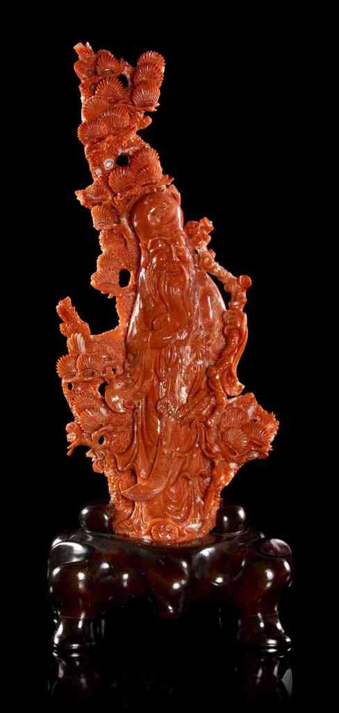 A Coral Carving of a Shoulao, Height of coral 11 in: A Coral Carving of a Shoulao, depicting the god of longevity with exaggerated cranium on the natural form branch with carved shell decoration throughout, raised upon a fitted hardwood base. Height of 