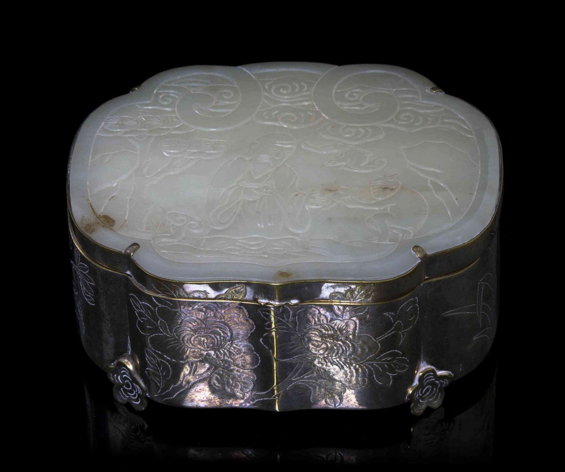 A White Jade Plaque from a Ruyi Scepter, Width 4 3: A White Jade Plaque from a Ruyi Scepter, of shaped form with carving of a landscape scene, mounted in a silver metal box of conforming shape. Width 4 3/4 inches. Property from the Estate of Dr. Joseph