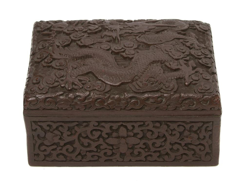 A Chinese Cinnabar Lacquer Lidded Box, Height 2 1/: A Chinese Cinnabar Lacquer Lidded Box, of rectangular form, the lid carved with a sinuous five-clawed dragon amongst clouds, the sides carved with scrolling foliate motif, having inset gilt metal Qian