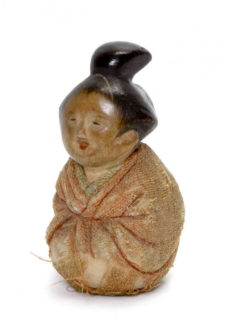 A Japanese Cloth Covered Doll with Wood Head, Heig: A Japanese Cloth Covered Doll with Wood Head, depicting a young girl with painted decoration to the hair and face, wrapped in a red and green cloth robe. Height 1 3/8 inches. Provenance: Ex Frances Bu
