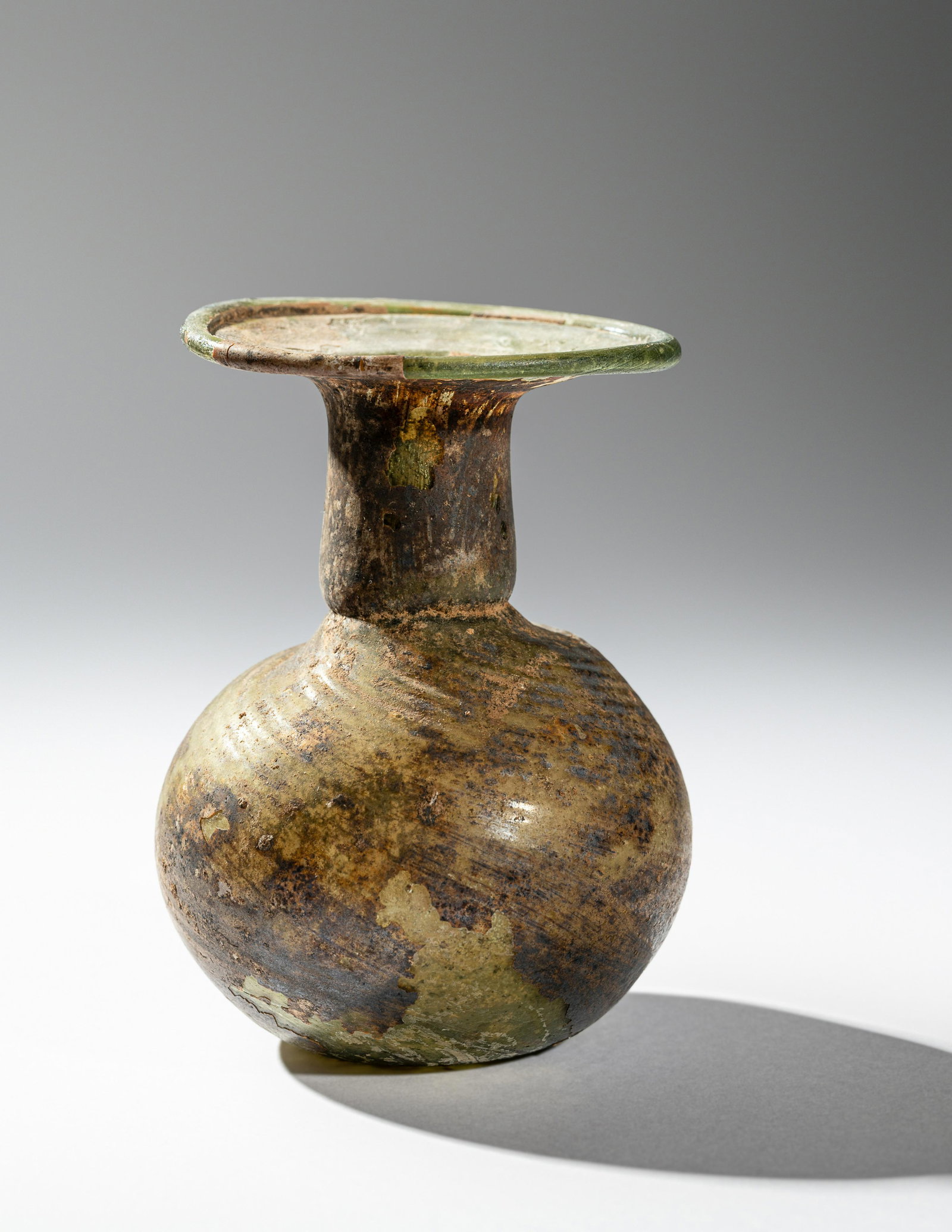 A Roman Green Glass Bottle: A Roman Green Glass Bottle Circa 2nd Century A.D. Height 3 3/4 inches (9.5 cm). Provenance: Private Estate, Connecticut, acquired in the mid-1980s.