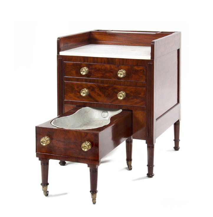 An American Classical Mahogany Commode Cabinet, Hei: An American Classical Mahogany Commode Cabinet, having galleried marble top with fitted compartments over two drawers and pullout chamber pot, raised on ring turned legs ending in casters. Height 32 3