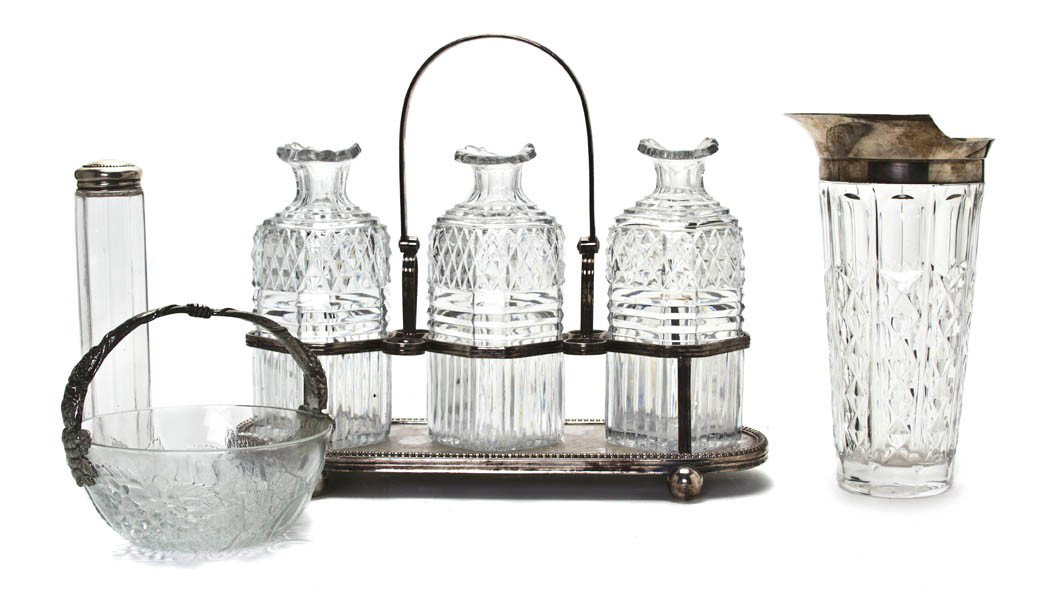 An English Silverplate and Cut Glass Cruet Set, Wi: An English Silverplate and Cut Glass Cruet Set, having swing handle over squared bottles with diamond cut, raised on an oval base with spherical feet, together with a molded glass and silverplate cock