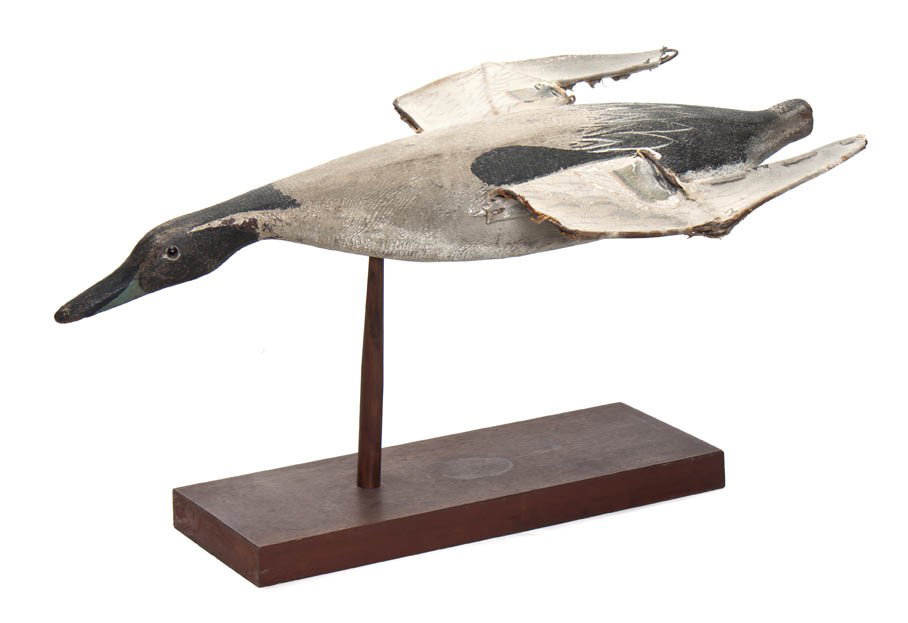 A Carved Wood and Polychrome Decorated Decoy, Leng: A Carved Wood and Polychrome Decorated Decoy, depicting a duck modeled in flight with canvas wings. Length 25 inches.