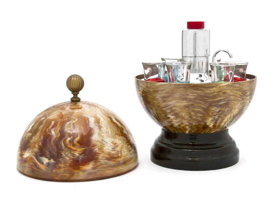 An Art Deco Style Composite Drinks Dispenser, Dia: An Art Deco Style Composite Drinks Dispenser, of spherical form, the top lifting to reveal six shot glasses and the liquor pump. Diameter 8 1/2 inches.
