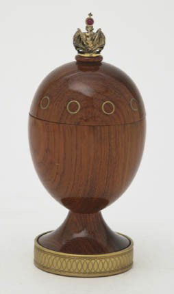 A Theo Faberge Turned Mahogany and Brass Inset Egg: A Theo Faberge Turned Mahogany and Brass Inset Egg, having a crown finial and incised brass base, set in a fitted case. Height 5 inches.