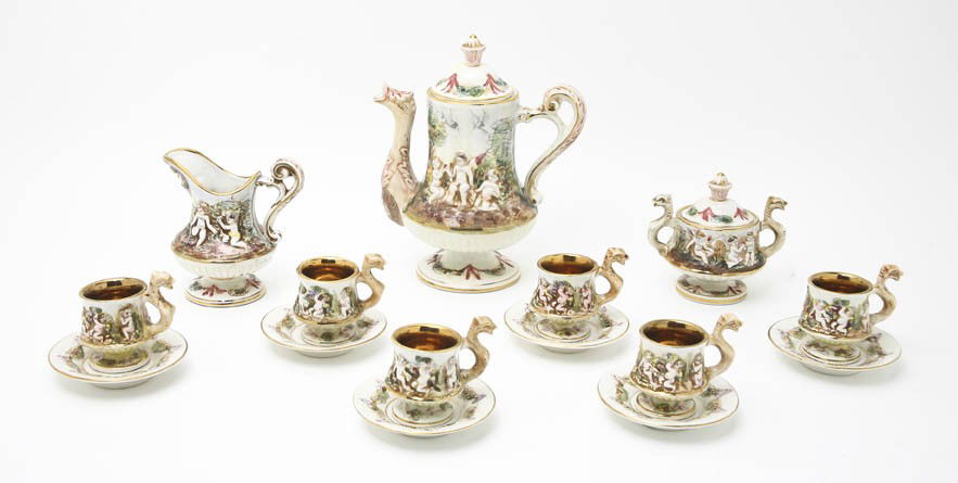 A Capodimonte Tea Service, Height of first 9 inche: A Capodimonte Tea Service, 20th century, comprising a teapot, creamer, six covered sugar cups and six saucers, each decorated with mythical figures in relief. Height of first 9 inches.