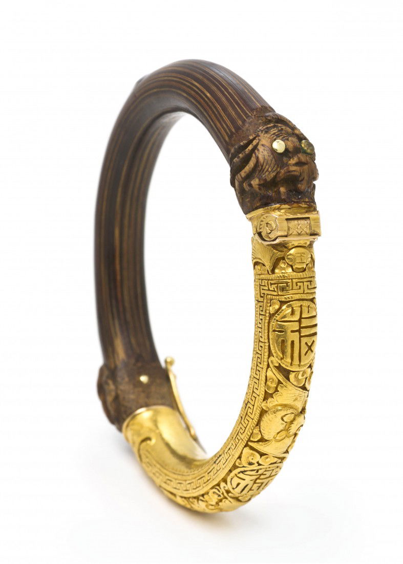 A Yellow Gold and Bamboo Bracelet, Chinese, 25.40: A Yellow Gold and Bamboo Bracelet, Chinese, consisting of a deeply textured gold section depicting bats and characters, opposite side in carved bamboo, hidden clasp. Stamp: Bao Feng Zu Jin (indicating
