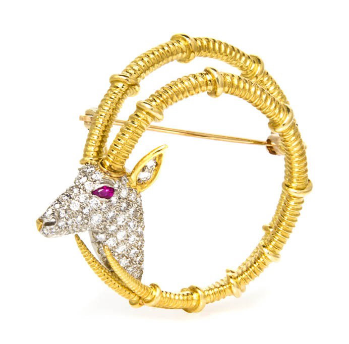 An 18 Karat Gold, Diamond and Ruby Ibex Brooch, Je: An 18 Karat Gold, Diamond and Ruby Ibex Brooch, Jean Schlumberger for Tiffany & Co., depicting the head and antlers of an ibex, containing one pear shape checkerboard top ruby eye and numerous round b