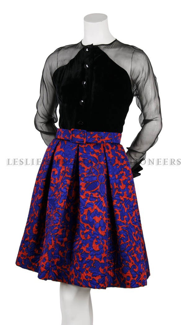 A Givenchy Printed Silk Dress, Size 38.: A Givenchy Printed Silk Dress, 1980s, with sheer raglan sleeves, black velvet cuffs and bodice, decorative buttons, violet and red printed skirt with box pleats, matching belt, fully lined. Labeled: G