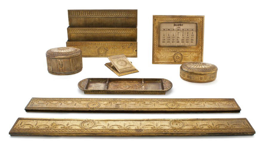 An Assembled Tiffany Studios Gilt Bronze Desk Set,: An Assembled Tiffany Studios Gilt Bronze Desk Set, in the Adams pattern, comprising blotter ends, letter rack (1779), paperclip (1783), inkwell (1777), pen tray (1778), calendar (0908) and a stamp box