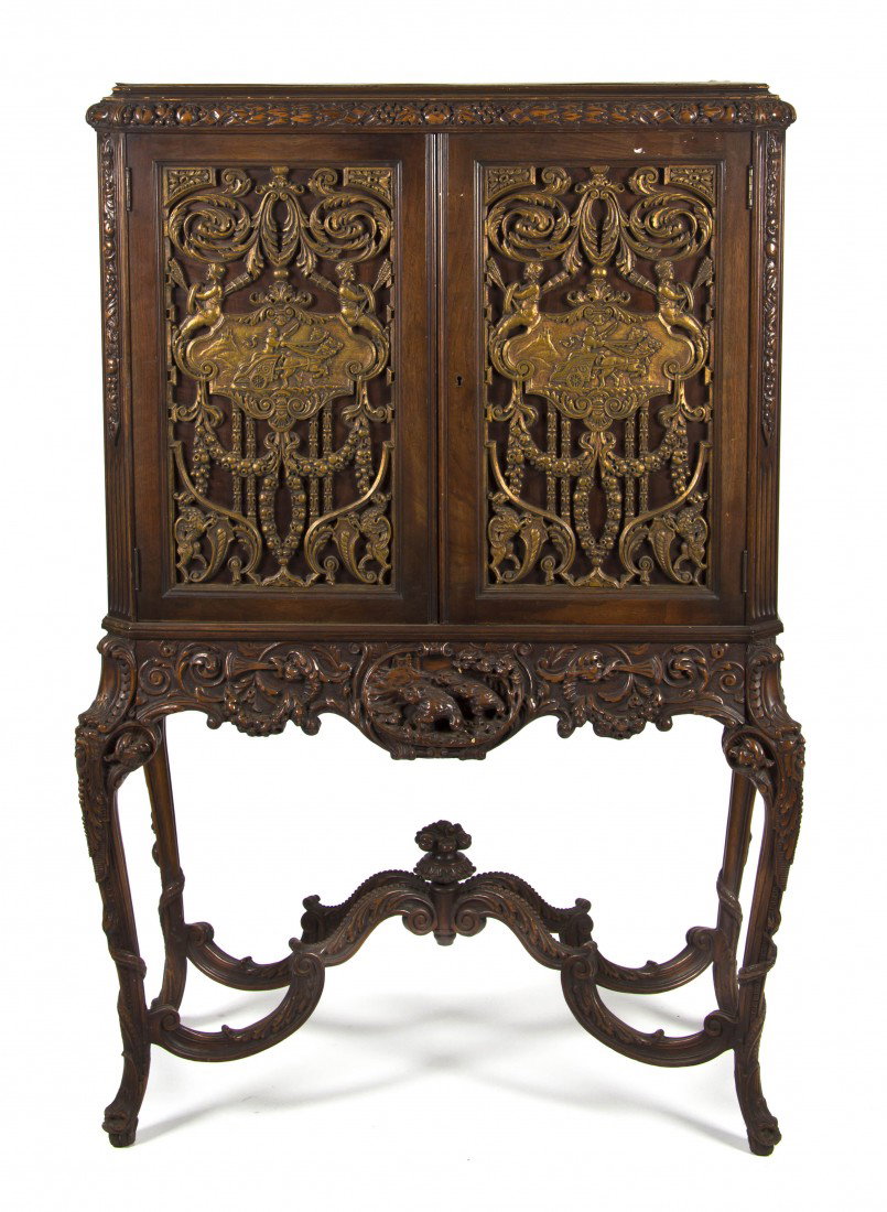 A Continental Cabinet on Stand, Height 63 x width: A Continental Cabinet on Stand, the carved cornice above two doors opening to reveal burlwood drawers, the whole raised on foliate carved legs terminating in dolphin form feet joined by a scroll carve