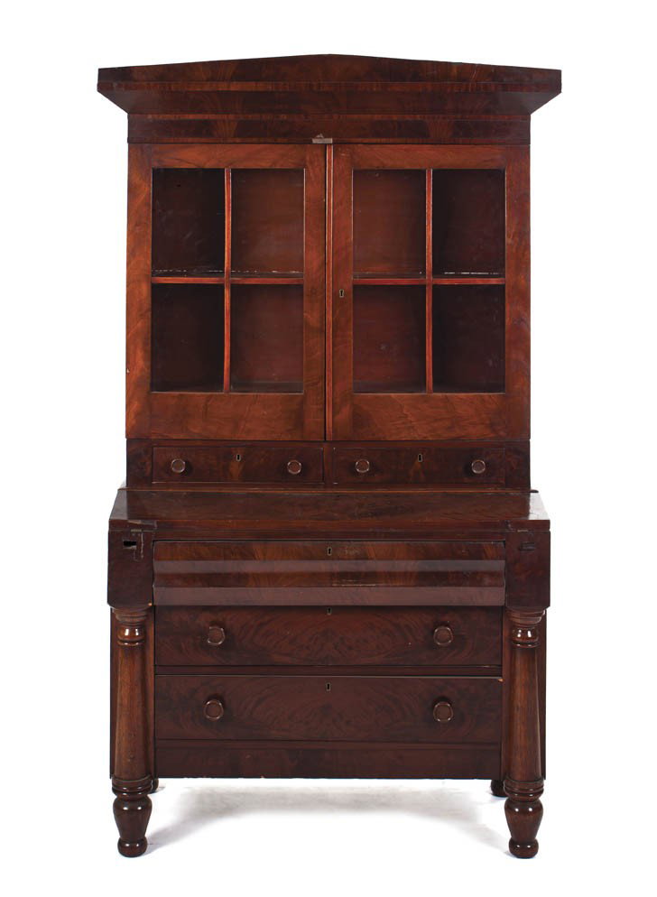 An American Empire Mahogany Secretary Bookcase, He: An American Empire Mahogany Secretary Bookcase, in two parts, the superstructure having a peaked cornice over two glazed doors above two drawers the base set with fall front writing surface over three