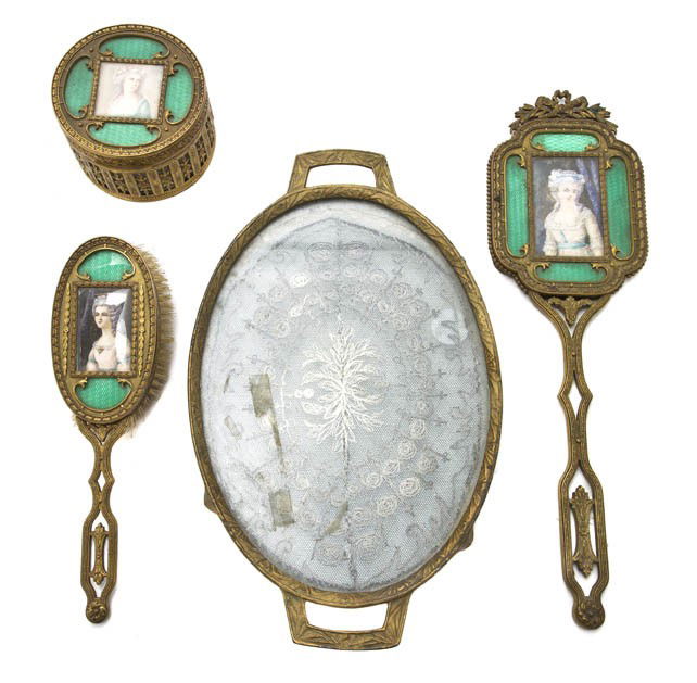 An Assembled Gilt Metal Dresser Set, Width of fir: An Assembled Gilt Metal Dresser Set, comprising a handled tray, a powder box, a hand mirror and brush, the latter three each set with a portrait of a lady. Width of first 13 inches.