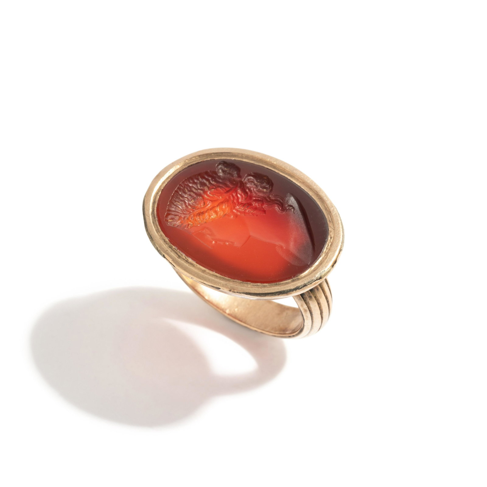 A Neoclassical Carnelian and Brass Finger Ring with a Bust of a Deity: A Neoclassical Carnelian and Brass Finger Ring with a Bust of a Deity Ring size 17.5 mm; 4.1 dwt.