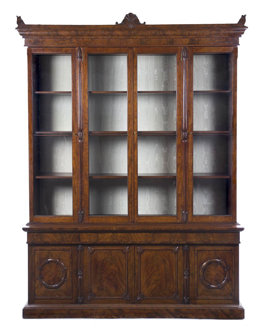 A William IV Mahogany Bookcase, Height 102 x width : A William IV Mahogany Bookcase, second quarter 19th century, having a molded frieze with carved acanthus leaf accents over four glazed doors above four paneled doors raised on a plinth base. Height 10