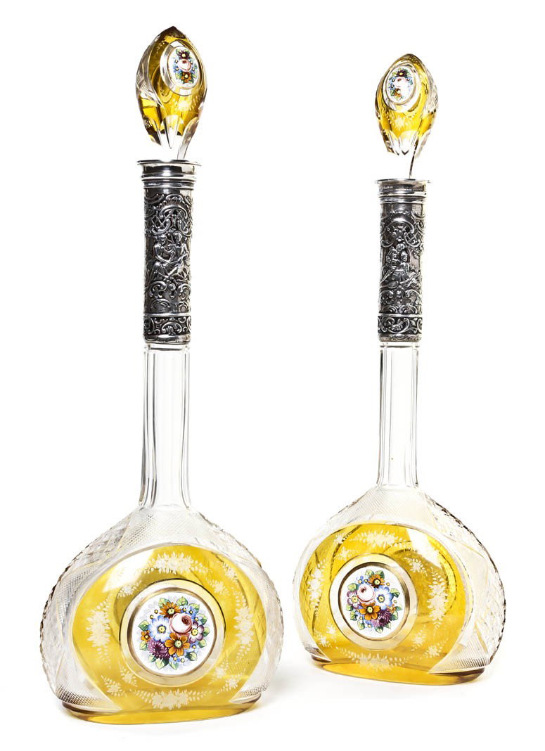 A Pair of Bohemian Silver Mounted and Enameled Gla: A Pair of Bohemian Silver Mounted and Enameled Glass Decanters, each in amber cut to clear glass having an elongated neck set with a repousse decorated flange depicting a courting couple, the stoppers