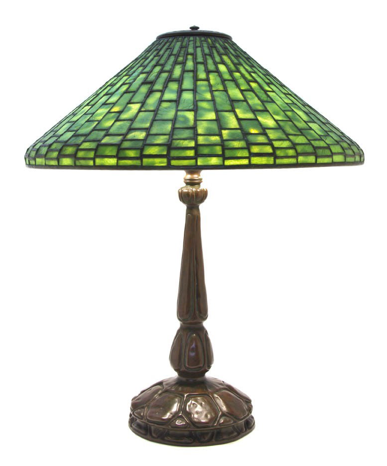 A Tiffany Studios Favrile Glass and Bronze Geometr: A Tiffany Studios Favrile Glass and Bronze Geometric Table Lamp, the heat cap over the conical shade fitted with mottled green rectangular tiles, raised on the bronze base ending in a circular foot wi