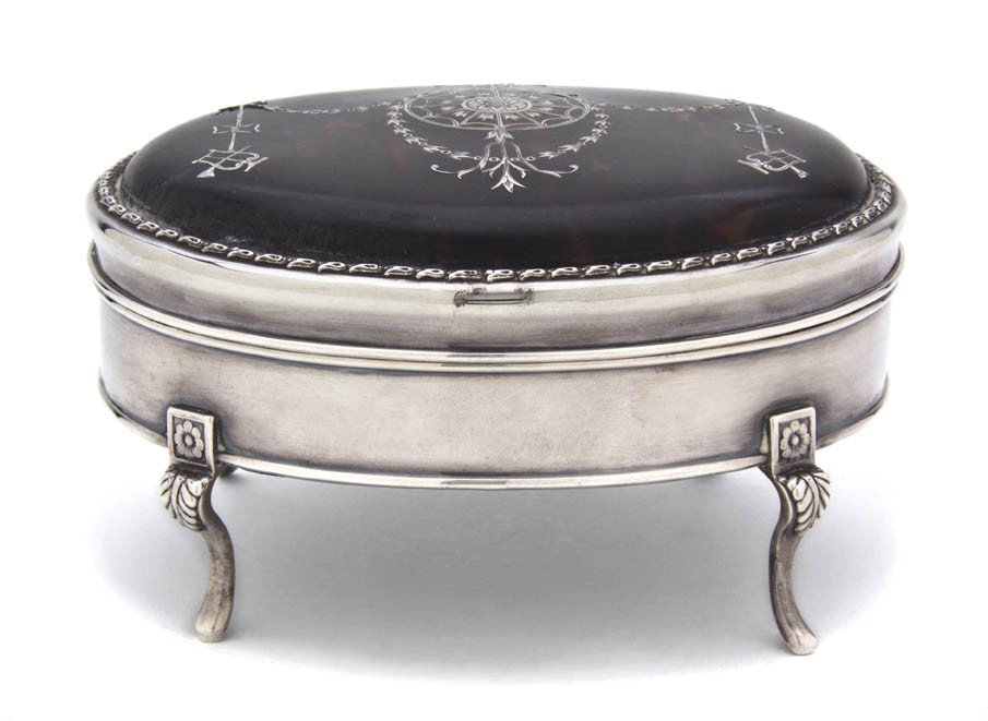 An English Silver and Tortoise Shell Table Casket,: An English Silver and Tortoise Shell Table Casket, Charles and Richard Comyns, London, 1918, of oval, footed form, the hinged lid with ribbon-tied festoon inlaid decoration. Width 6 1/8 inches. Proper