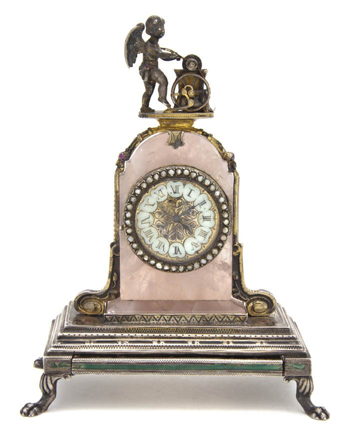 A Continental Judaica Enameled, Gem Inset, Silver: A Continental Judaica Enameled, Gem Inset, Silvered and Gilt Metal Table Clock Menorah, surmounted with Cupid sharpening his arrow, having a hidden slide out compartment, above the arched rose quartz 