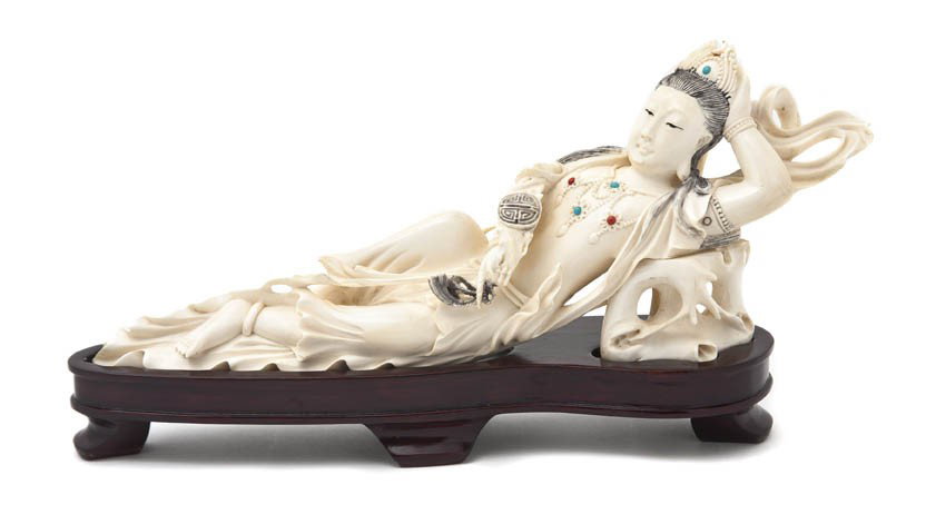 A Carved Chinese Ivory Figure, Width 11 inches.: A Carved Chinese Ivory Figure, depicting a recumbent lady, having inset stones to her crown and necklace, modeled in flowing garments and holding a ruyi scepter, raised upon a fitted hardwood base. Wi