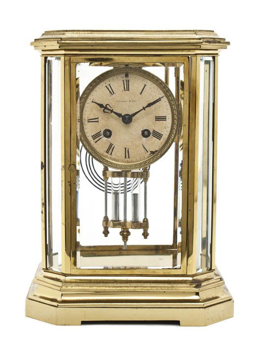 An American Brass and Glass Carriage Clock, Tiffany: An American Brass and Glass Carriage Clock, Tiffany & Co. having an octagonal molded top over the conforming case, the enameled dial with Roman numeral hours and having a faux mercury pendulum, raised