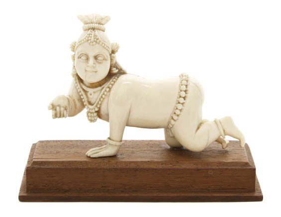 A Southeast Asian Carved Ivory Model of Krishna, L: A Southeast Asian Carved Ivory Model of Krishna, depicted in a recumbent pose with carved strands of beads throughout and holding a sphere in one raised hand. Length 3 1/4 inches. Property from the Es