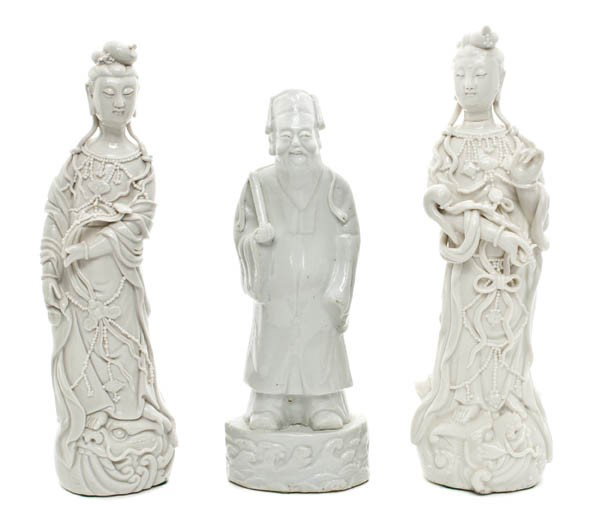 A Pair of Chinese Porcelain Figures of Guanyin, He: A Pair of Chinese Porcelain Figures of Guanyin, each depicted holding a ruyi scepter and having beaded strands and flowing robes, together with a figure of a male immortal raised on a base with wave f