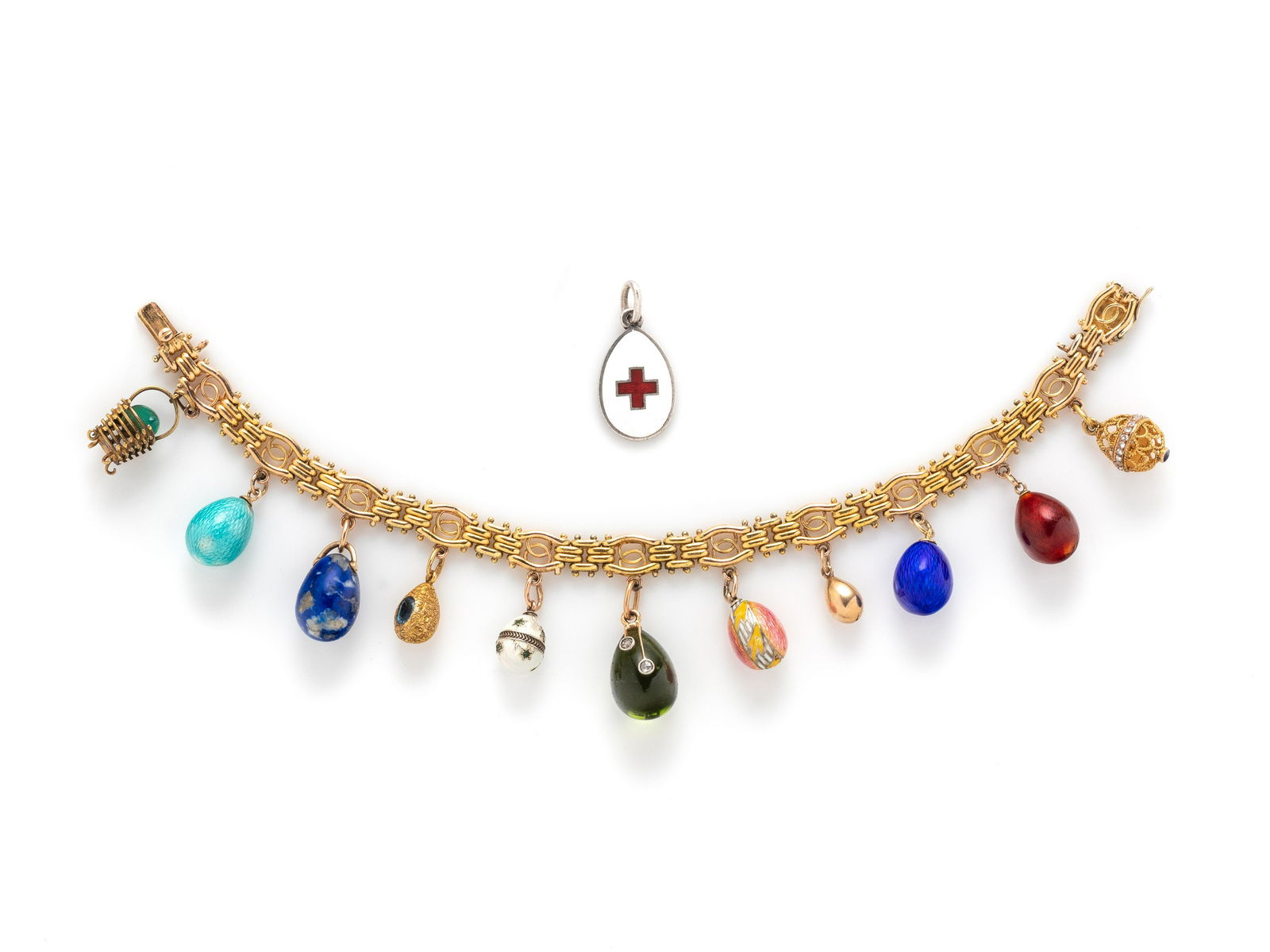 RUSSIAN, ANTIQUE, YELLOW GOLD AND ENAMEL EGG CHARM BRACELET: RUSSIAN, ANTIQUE, YELLOW GOLD AND ENAMEL EGG CHARM BRACELET Consisting of a fancy link bracelet suspending a carved green chrysoprase egg in a gold wirework basket, a turquoise colored enameled egg, a