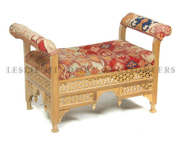 An Eastern Style Window Bench, Height 26 inches.: An Eastern Style Window Bench, having kilim upholstered seat and arms over pierce carved open fretwork, raised on turned legs. Height 26 inches.