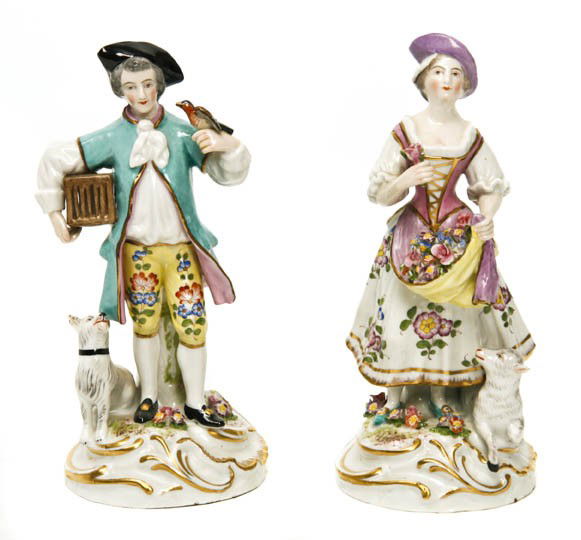 A Pair of Continental Porcelain Figures, Bloch, H: A Pair of Continental Porcelain Figures, Bloch, the first depicting a gentleman bird catcher and his dog, the second a shepherdess with her skirt full of flowers, both having crossed arrows mark in un
