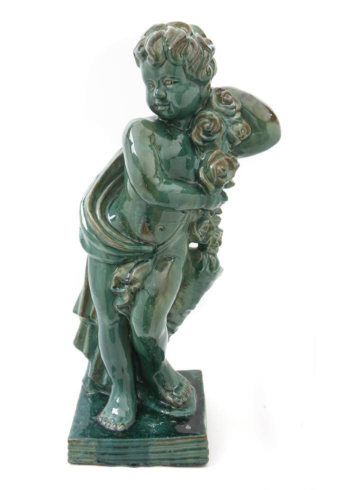 A Glazed Ceramic Figure, Height 28 1/4 inches.: A Glazed Ceramic Figure, depicting a standing draped putto holding a garland of roses and standing before a stump, set on a square base. Height 28 1/4 inches.