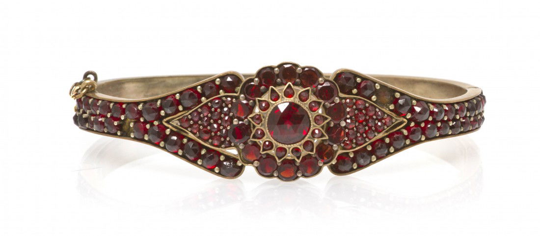 A Gold Tone and Garnet Bangle Bracelet, 13.70 dwts: A Gold Tone and Garnet Bangle Bracelet, containing numerous round and pear shape rose cut garnets. 13.70 dwts. Property from the Lucie Sable Sandler Trust, Lincolnwood, Illinois
