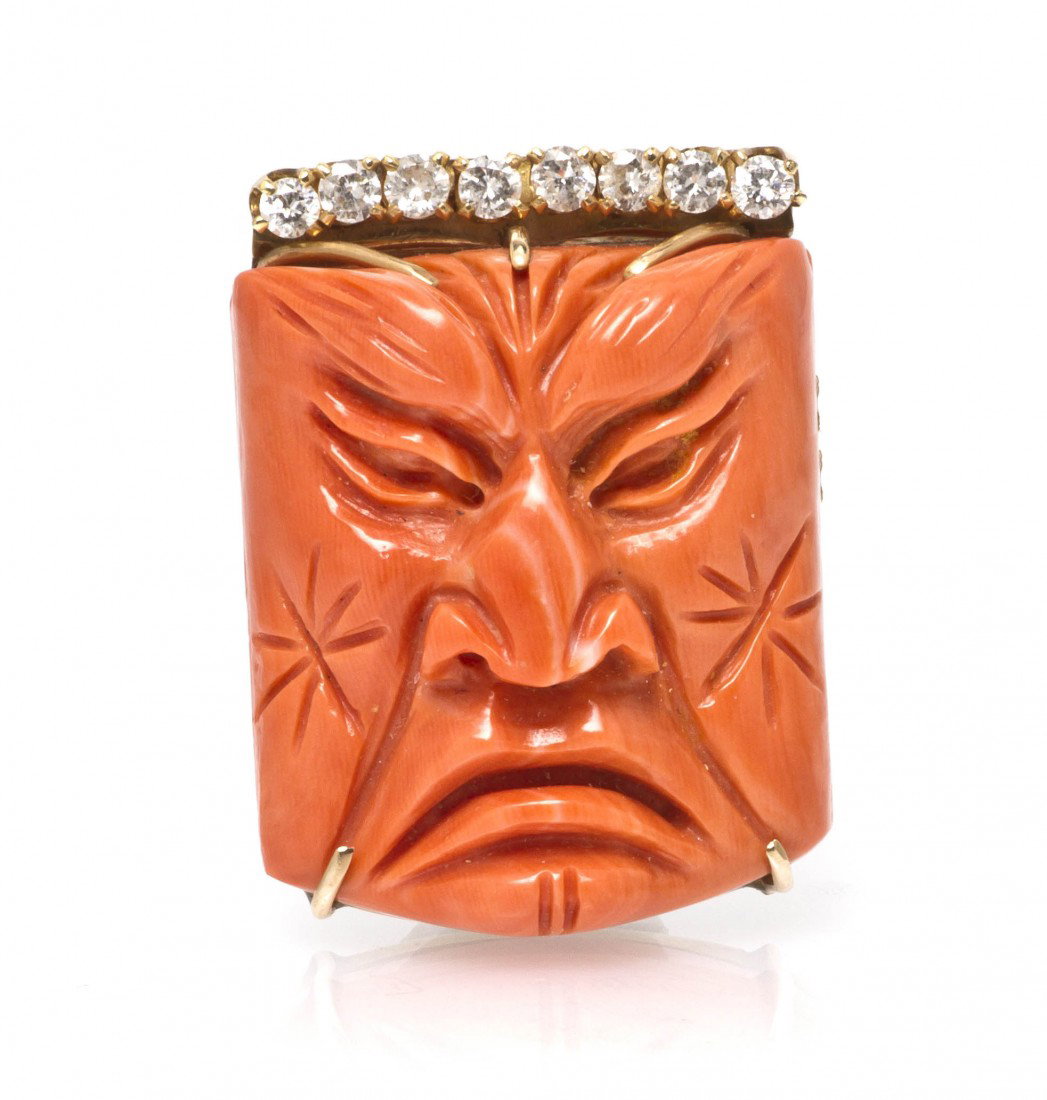 An 18 Karat Yellow Gold, Coral and Diamond Motif B: An 18 Karat Yellow Gold, Coral and Diamond Motif Brooch, consisting of a central Asian motif orange red coral carving of a face within a gold setting containing eight round brilliant cut diamonds weig