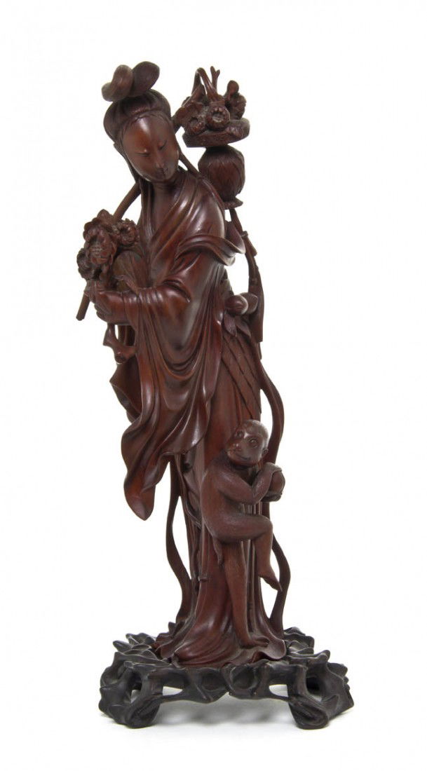 A Chinese Boxwood Carving of a Woman and a Monkey,: A Chinese Boxwood Carving of a Woman and a Monkey, depicting the standing beauty holding a basket of flowers on a stick and with a monkey at her feet, raised atop a pierce carved wood stand. Height of