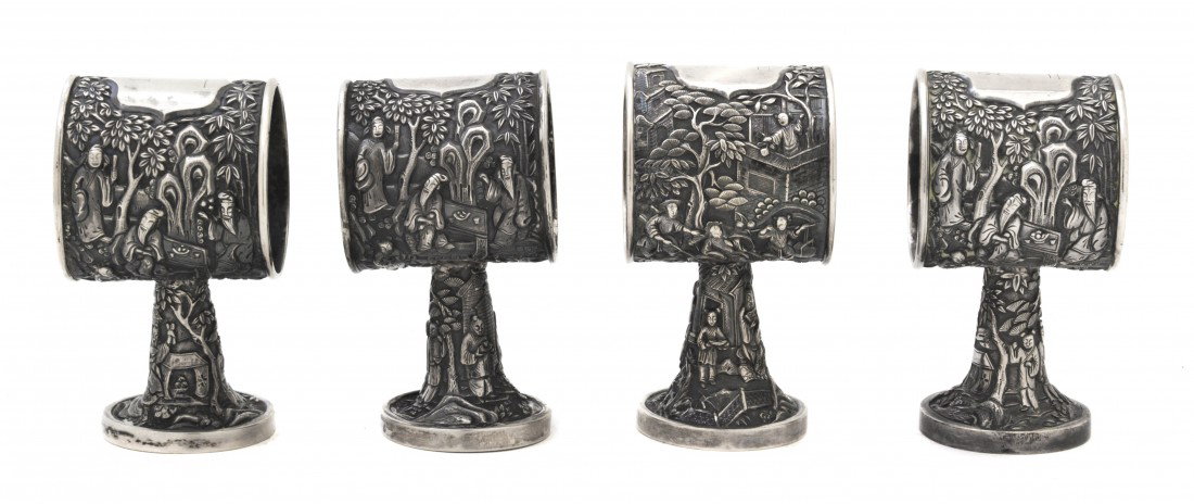 A Set of Four Chinese Export Silver Napkin Rings, : A Set of Four Chinese Export Silver Napkin Rings, late 19th century, in the manner of Leeching, having embossed decoration of an old man seated at a table with food surrounded by foliage and with an a