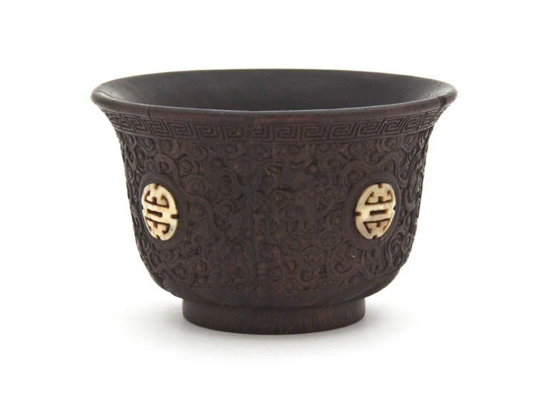 A Chinese Zitan Carved Cup, Height 2 3/16 x diamet: A Chinese Zitan Carved Cup, the main body carved with scrolling decoration of clouds interspersed with bats, containing four inset bone medallions, the slightly flared mouth rim having key-fret border