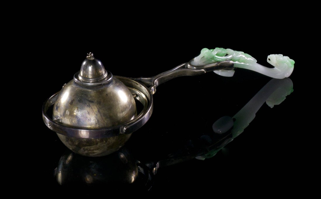 A Jadeite Belt Hook and Silver Mounted Cigar Light: A Jadeite Belt Hook and Silver Mounted Cigar Lighter, the hook of apple green and white colored stone with a sinuous chilong on the back, mounted with a spherical silver ball and stamped S&G Gump Co. 
