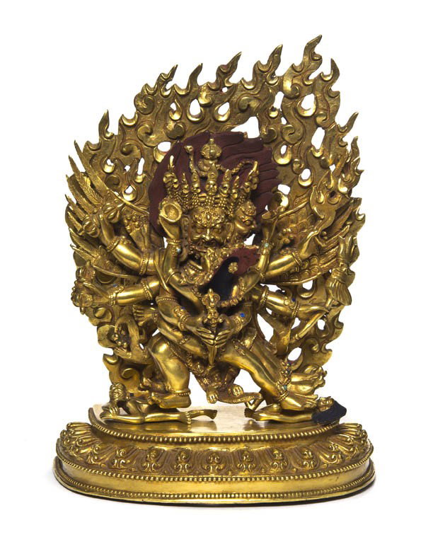 A Southeast Asian Gilt Bronze Figure of a Deity, H: A Southeast Asian Gilt Bronze Figure of a Deity, depicting a winged deity embracing another, holding multiple vajra and daggers, the two figures standing atop two figures, raised atop a base with lapp